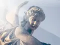 Kamienna rzeźba anioła, z promieniem światła padającym na twarz. Wzrok skierowany w dół, jakby w modlitwie do anioła stróża o pomoc.