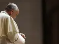 Papież Franciszek w białej szacie, z rękami złożonymi do modlitwy do Ojca Świętego.