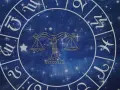 Zodiakalny krąg z symbolem Wagi w centrum. Wokół widoczne inne znaki powietrzne i gwiezdne tło.
