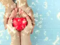 Dłonie trzymają czerwone serce, otoczone liczbami. Numerologia 5 i 11 symbolizuje harmonię i duchowość.