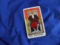Karta cesarz tarot, przedstawiająca władcę na tronie, leży na niebieskim tle.