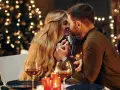 Romantyczny wieczór przy blasku świec i choinki. Para w intymnym uścisku, niczym rycerz kielichów uczucia, celebruje miłość.