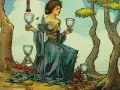 Kobieta w niebieskiej sukni trzyma kielichy, otoczona przez cztery kielichy tarot i czerwone owoce.