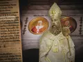 Starożytny tekst, w tym proroctwo Malachiasza, obok posągu papieża i portretów Franciszka, Benedykta XVI i Jana Pawła II.