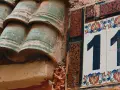 Numerologia partnerska 11 i 11. Dwa numery 11 na ozdobnych kafelkach, obok zielonych dachówek.