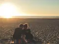 Para zakochanych na plaży o zachodzie słońca. Ich czoła się stykają, pokazując, jak kocha rak.