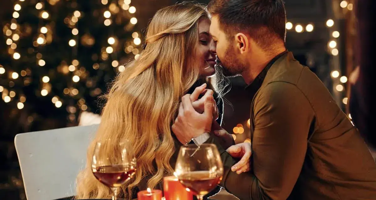 Romantyczny wieczór przy blasku świec i choinki. Para w intymnym uścisku, niczym rycerz kielichów uczucia, celebruje miłość.