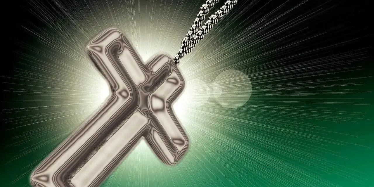 Srebrny krzyż na łańcuszku, symbol nadziei i modlitwy o nawrócenie grzeszników, otoczony blaskiem światła.