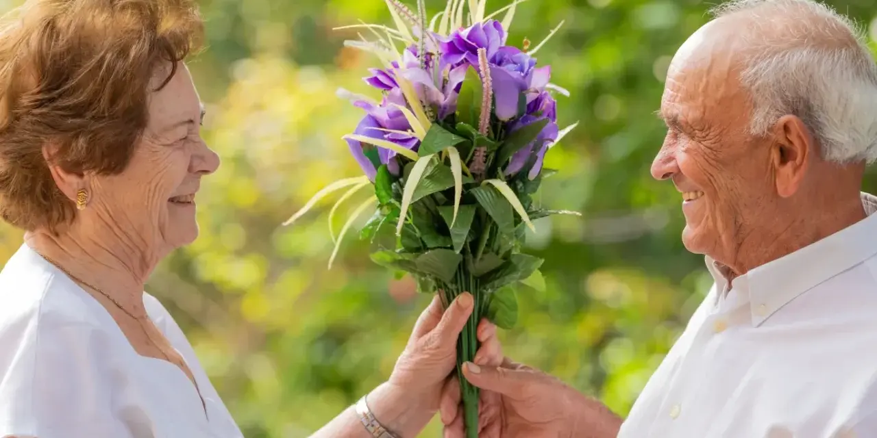 Starszy mężczyzna wręcza bukiet kwiatów kobiecie. Ich uśmiechy świadczą o głębokim, bliźniaczym związku, który trwa przez lata.