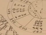 Zbliżenie na wykresy astrologiczne z symbolami planet i znaków zodiaku. Widoczny fragment horoskopu, gdzie 22.11 to znak zodiaku Strzelec.