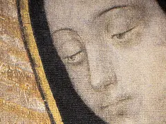 Zbliżenie na twarz z obrazu: łagodne oczy Matki Bożej z Guadalupe patrzą z ciemnego tła, otoczone złotym i czarnym obramowaniem.