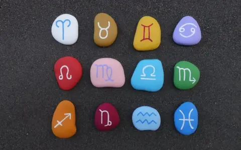 Kolorowe kamienie z symbolami zodiaku ułożone w rzędach. Widoczny jest znak zodiaku przed Koziorożcem, czyli Strzelec.