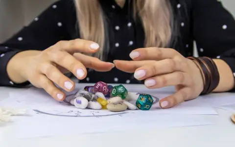 Dłonie nad kamieniami i kostkami z symbolami zodiaku. Czy wśród nich kryje się najsilniejszy znak zodiaku?