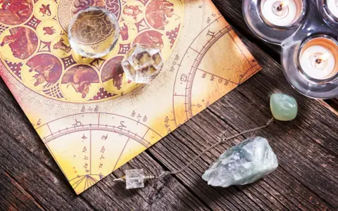 Numerologia 11 z dnia urodzenia. Kryształy, wahadło i świece na tle mapy astrologicznej.
