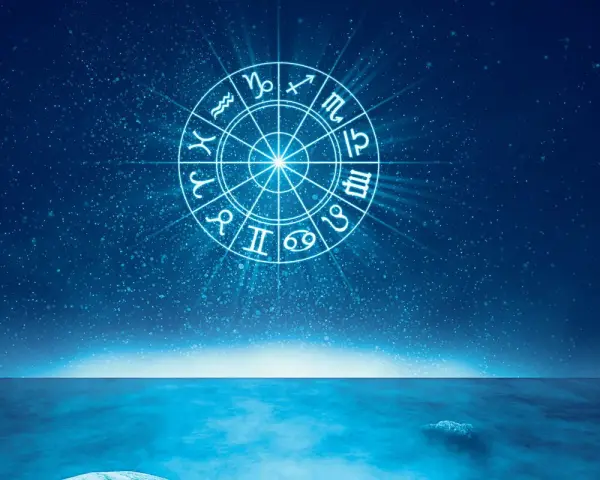 Jasny krąg zodiaku na tle nocnego nieba nad spokojnym morzem. Wodne znaki zodiaku wirują w kosmicznym tańcu.