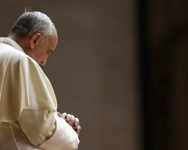 Papież Franciszek w białej szacie, z rękami złożonymi do modlitwy do Ojca Świętego.