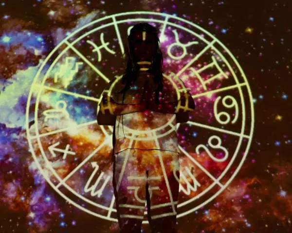 Postać w centrum, otoczona kosmiczną mgławicą, z projekcją ogniste znaki zodiaku na ciele.