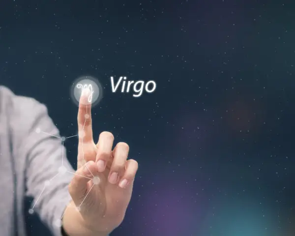 Dłoń dotyka symbolu Panny, gwiazdozbioru Virgo, na tle nocnego nieba.