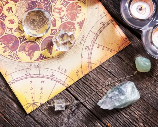 Numerologia 11 z dnia urodzenia. Kryształy, wahadło i świece na tle mapy astrologicznej.