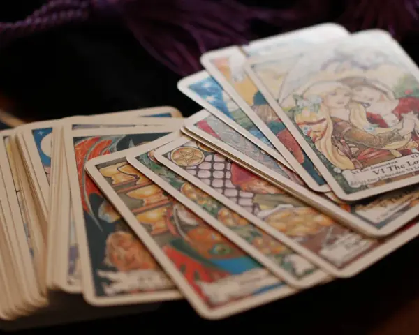 Karty tarota ułożone na drewnianym stole. Wśród nich widać kartę "Kochankowie". Sprawdź swój tarot tygodniowy skorpion.