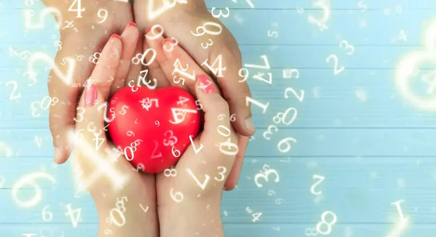 Dłonie trzymają czerwone serce, otoczone liczbami. Numerologia 5 i 11 symbolizuje harmonię i duchowość.