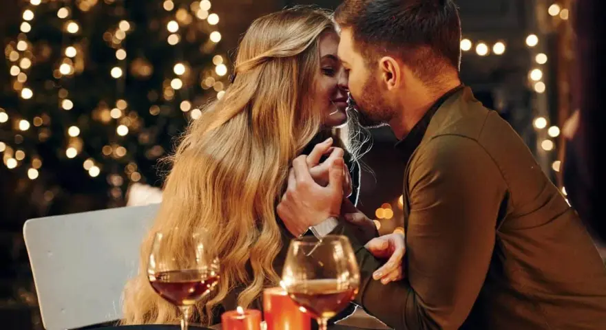 Romantyczny wieczór przy blasku świec i choinki. Para w intymnym uścisku, niczym rycerz kielichów uczucia, celebruje miłość.