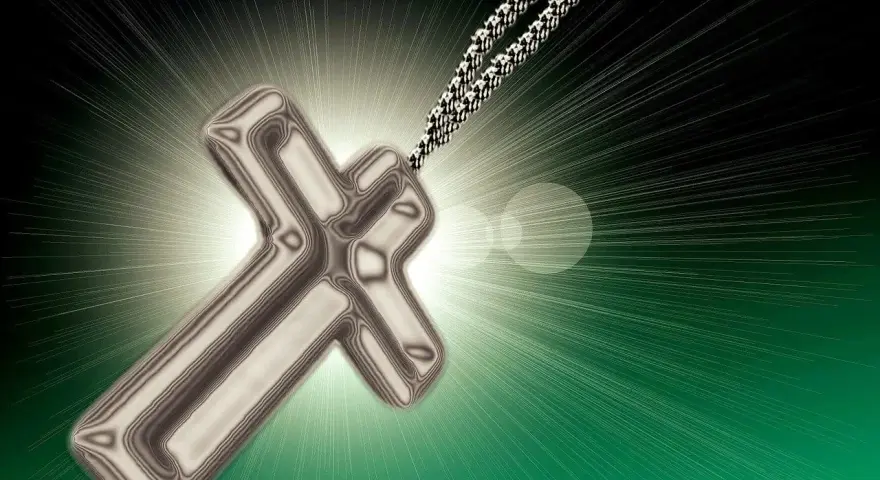 Srebrny krzyż na łańcuszku, symbol nadziei i modlitwy o nawrócenie grzeszników, otoczony blaskiem światła.