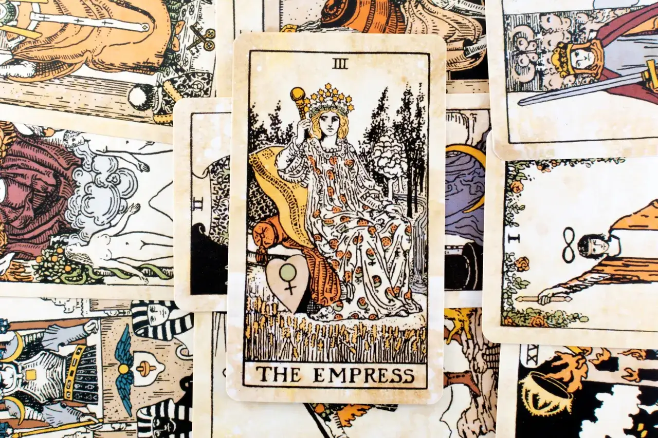 Karta cesarzowa tarot, III Arkanum Wielkie, przedstawia kobietę w koronie, siedzącą na tronie, otoczoną symbolami płodności i natury.