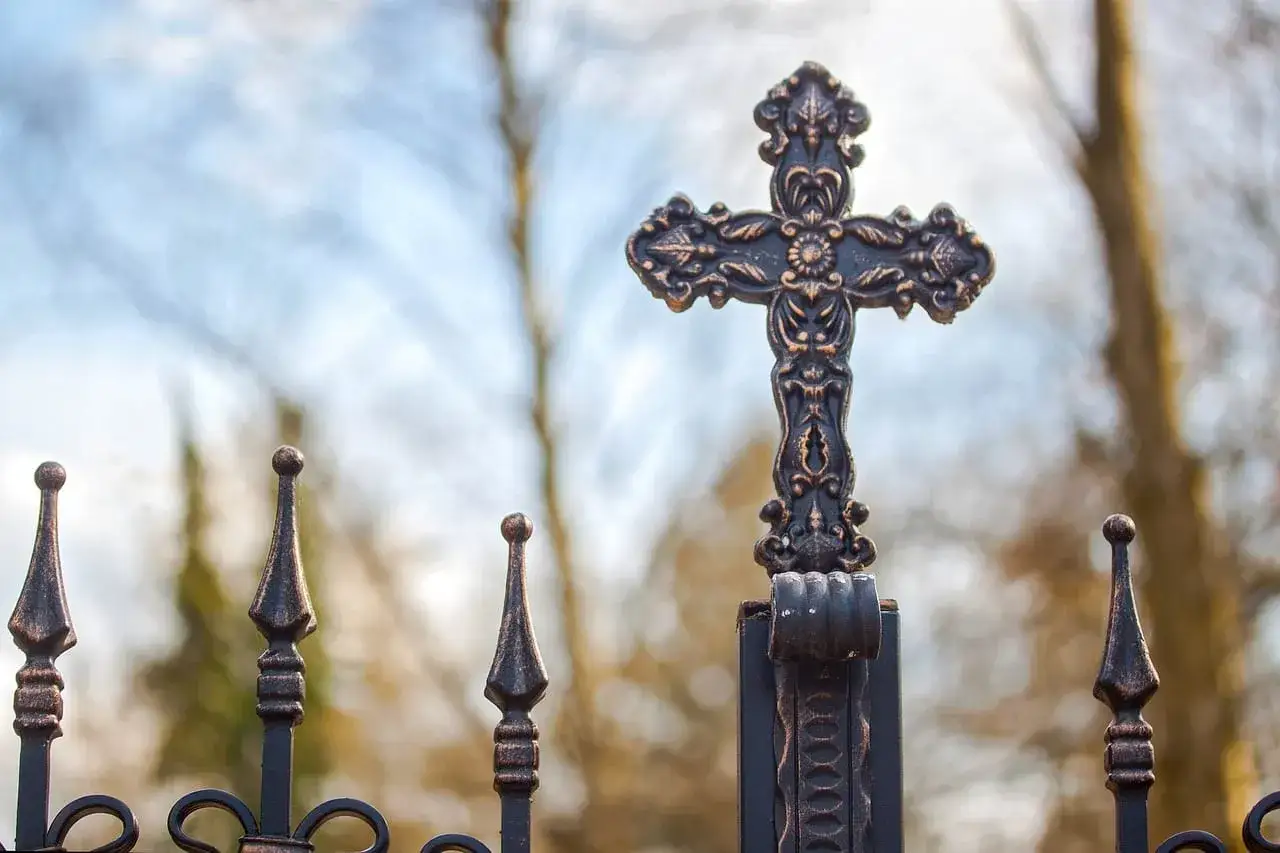Krzyż na metalowym ogrodzeniu. Czy znaki zodiaku to grzech? Pytanie wisi w powietrzu, gdy patrzymy na symbol wiary.