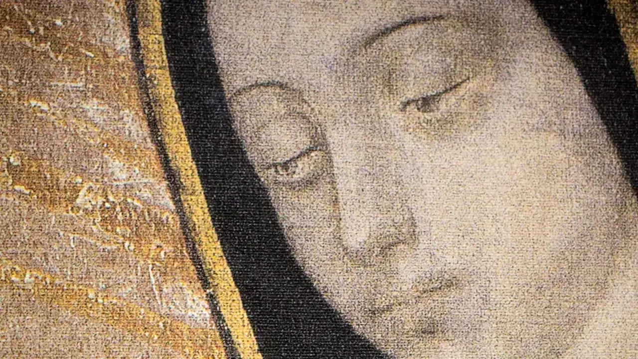 Zbliżenie na twarz z obrazu, ukazujące łagodne oczy Matki Bożej z Guadalupe, otoczone złotym i czarnym tłem.