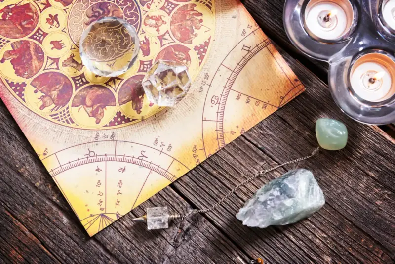 Numerologia 11 z dnia urodzenia. Kryształy, wahadło i świece na tle mapy astrologicznej.
